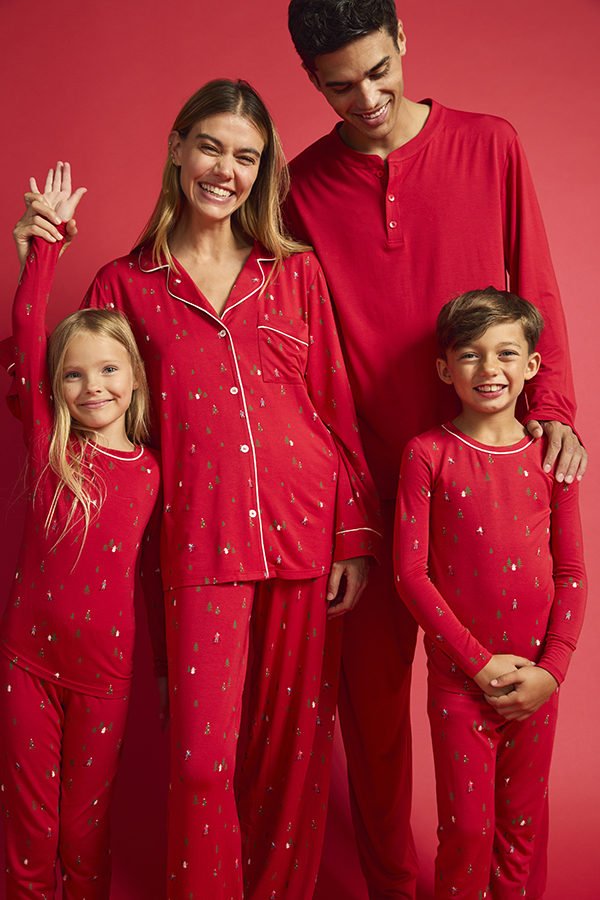 Editorial image of a family in red pajamas, plain backdrop, before retouch.