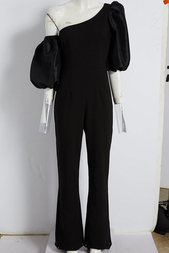 Simple, still-life ghost image of a black romper on mannequin, before retouching, visible stand, pinned up hem, and props