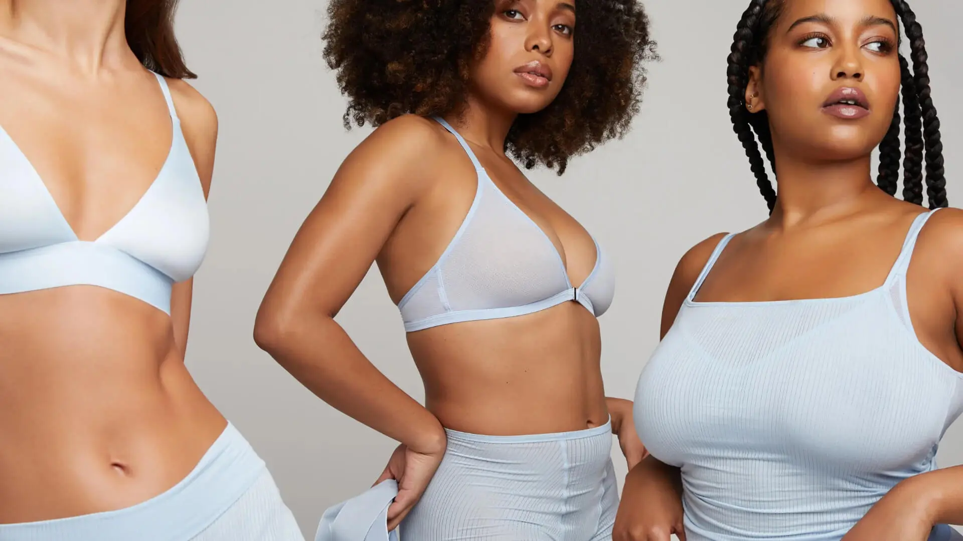 Three women of diverse body types and ethnicities pose confidently in light blue activewear, illustrating body positivity and inclusivity.