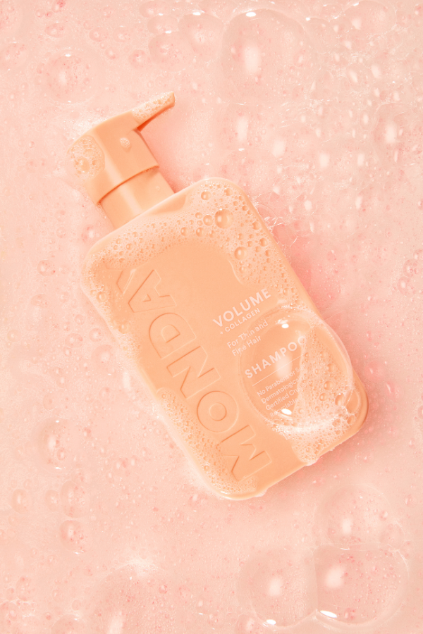 Monday Volume Shampoo bottle in a bubbly setting, highlighting creative and dynamic e-commerce product photography.